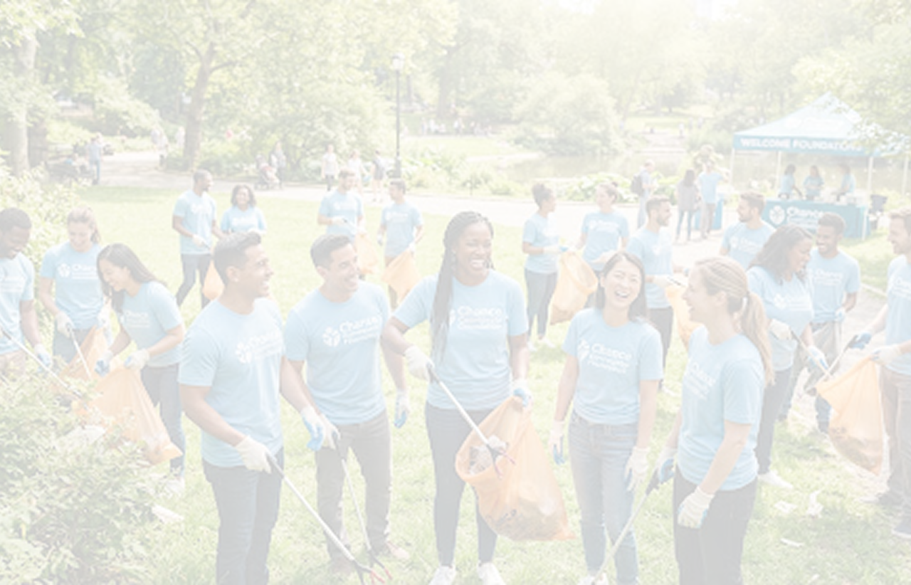 Group of volunteers smiling while collecting litter at a community park cleanup